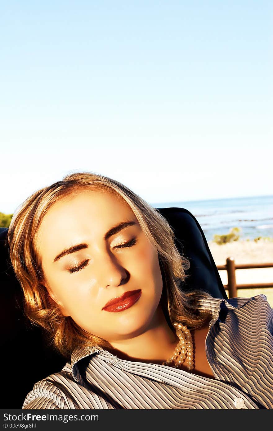 Portrait of a blonde woman sitting in the chair on holiday by the ocean.