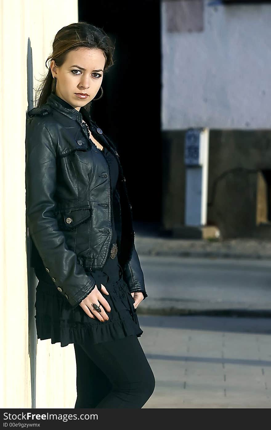 Attractive young woman posing leaning against a wall