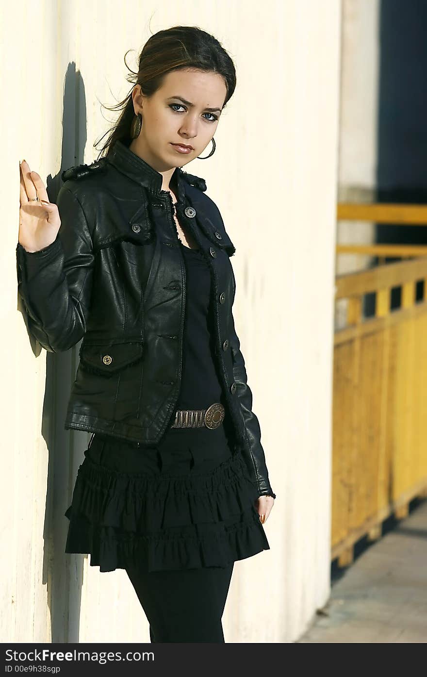 Attractive young woman posing leaning against a wall