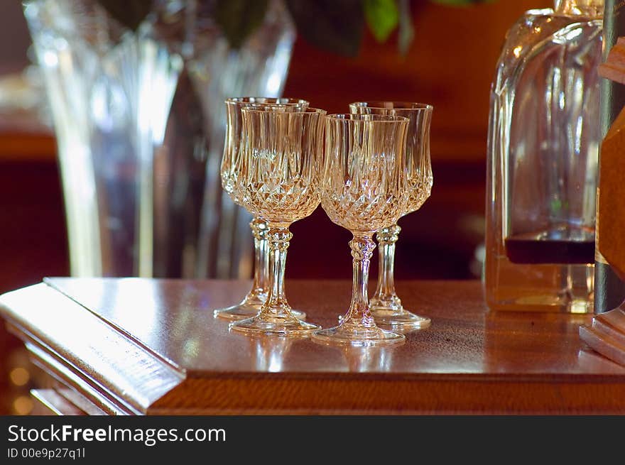 Crylstal glasses standing on  wooden cabinet in a formal lounge room. Crylstal glasses standing on  wooden cabinet in a formal lounge room