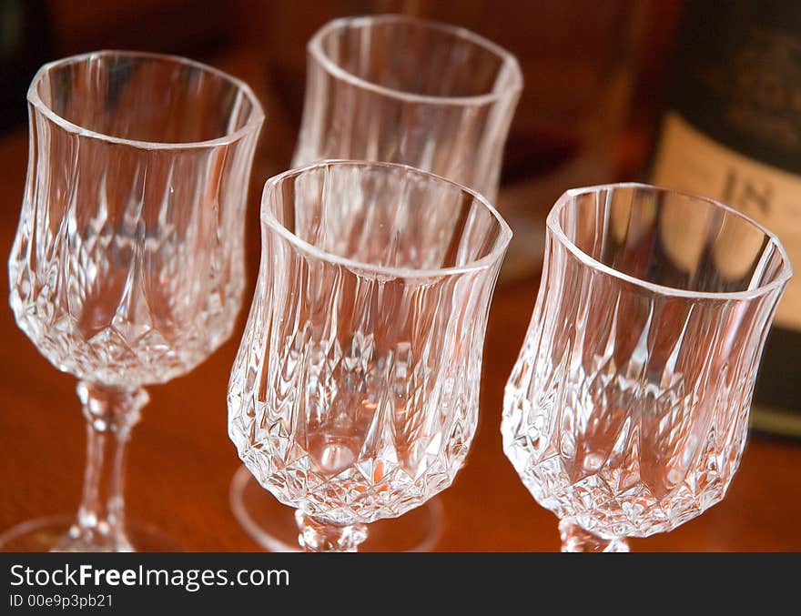 Crystal glasses displayed next to a bottle of scotch in a formal lounge room