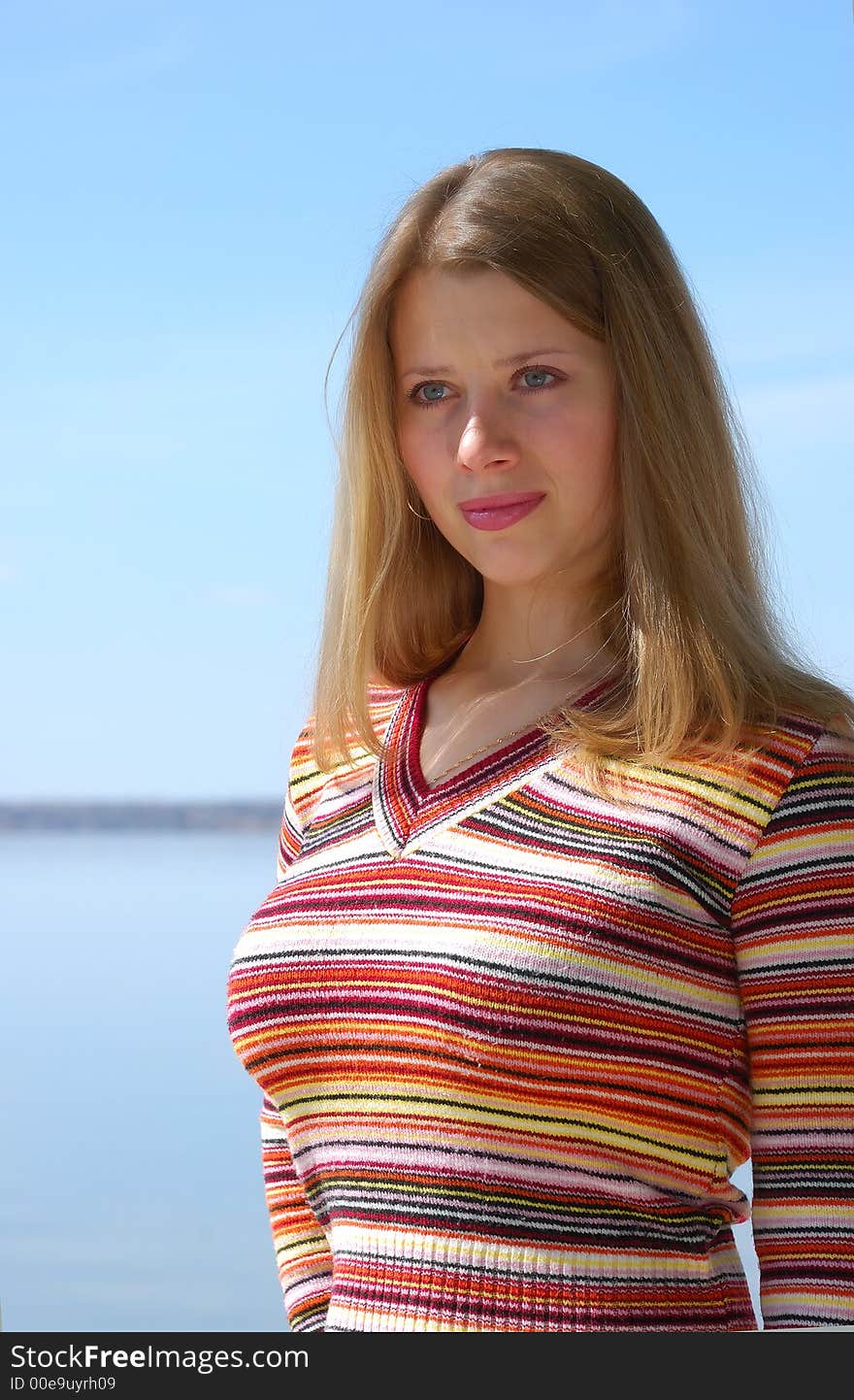 Girl on beach of river on blue sky background