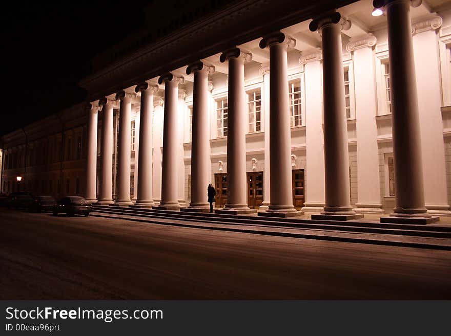 Girl - student at the entrance in university between pillars wait the car. Girl - student at the entrance in university between pillars wait the car