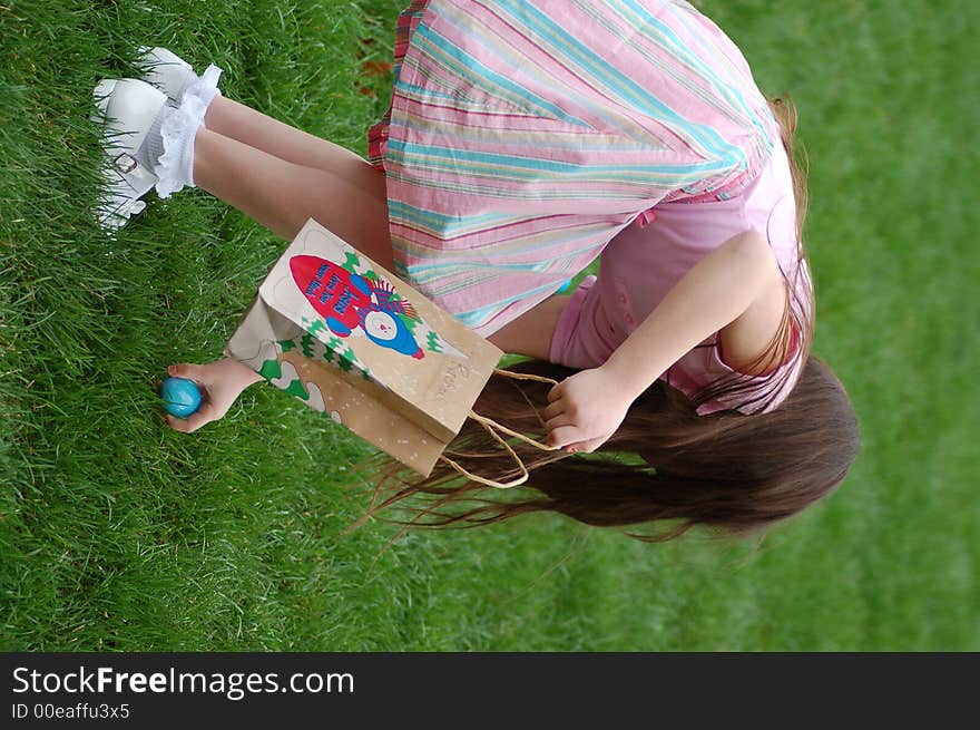 Little girl retrieving an easter egg into her bag. Little girl retrieving an easter egg into her bag.