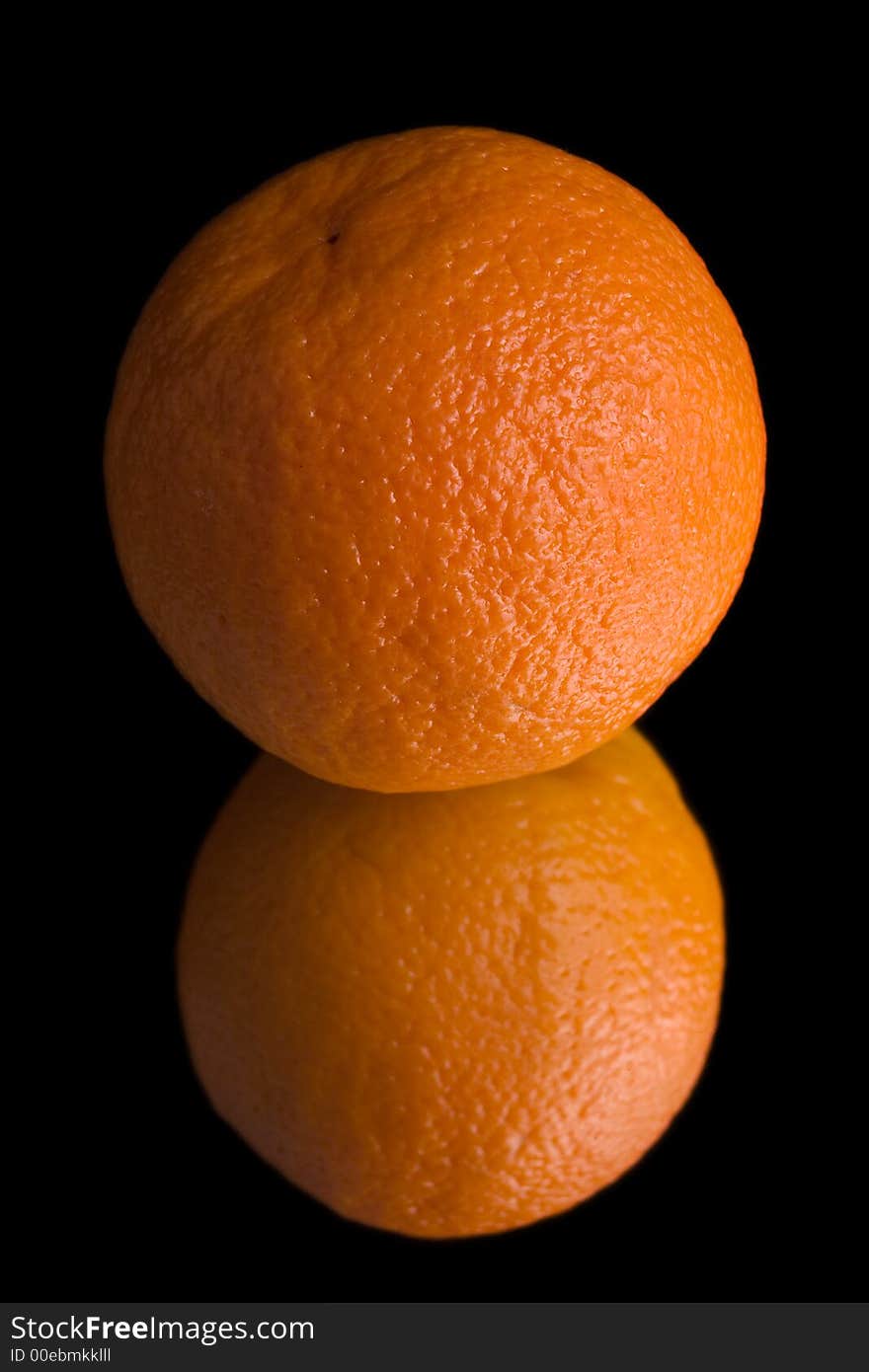 Old orange on mirror over black background