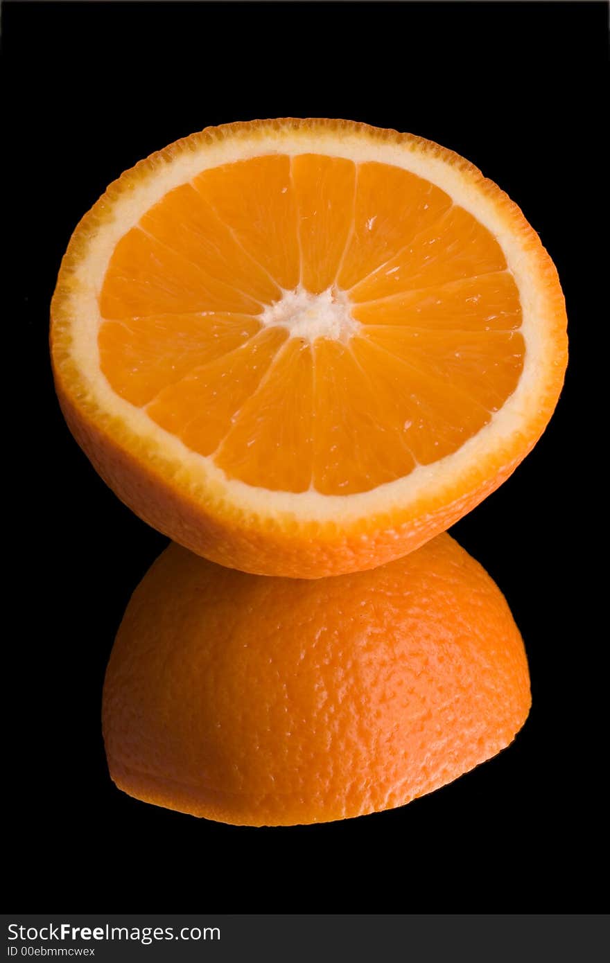 Sliced orange on mirror over black background