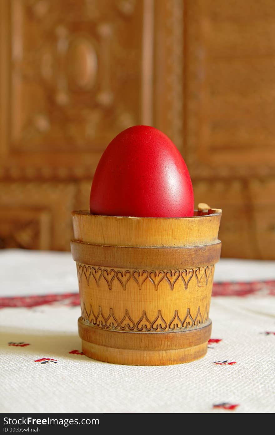 Red Easter egg in a traditional wooden canister with light reflection.