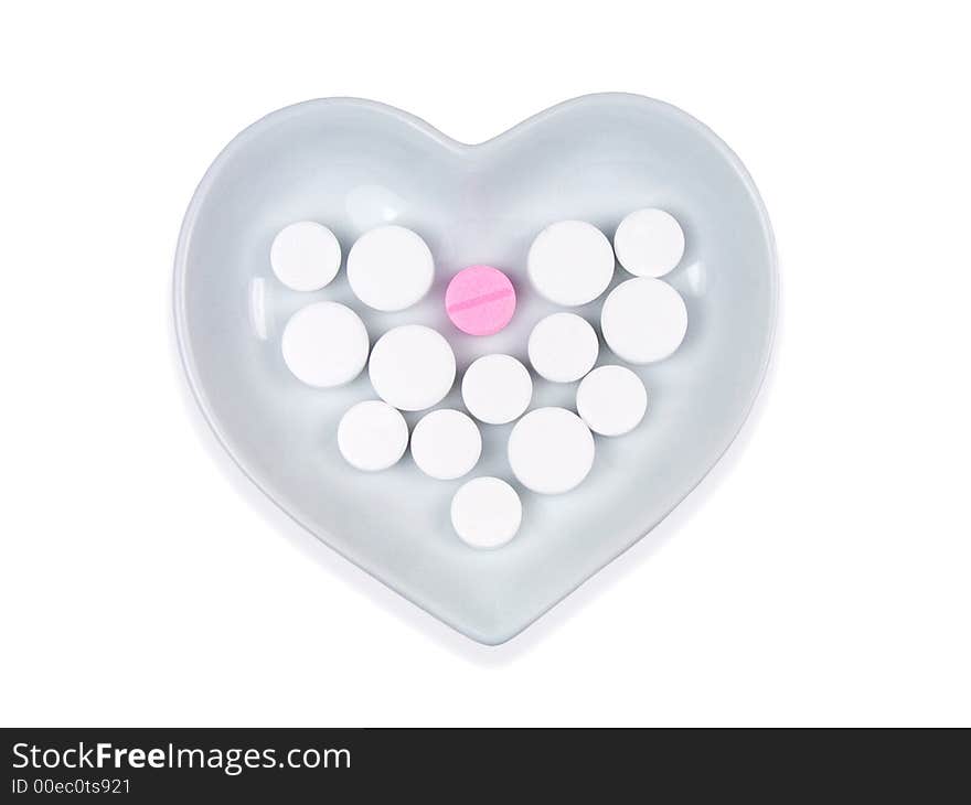 White and pink pills in a heart shaped bowl