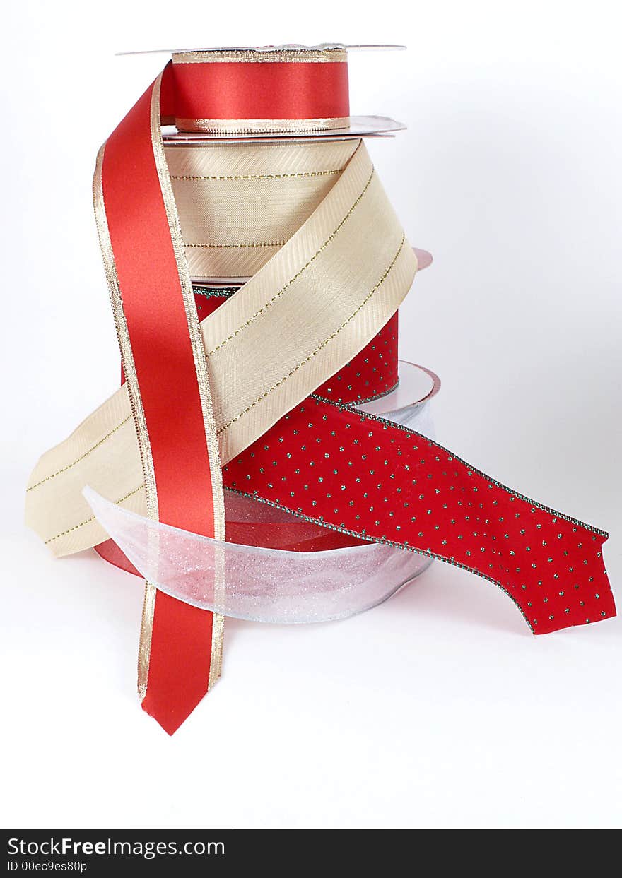 Tall stack of rolls of metallic ribbons in gold, red, and silver, isolated on white background. Tall stack of rolls of metallic ribbons in gold, red, and silver, isolated on white background