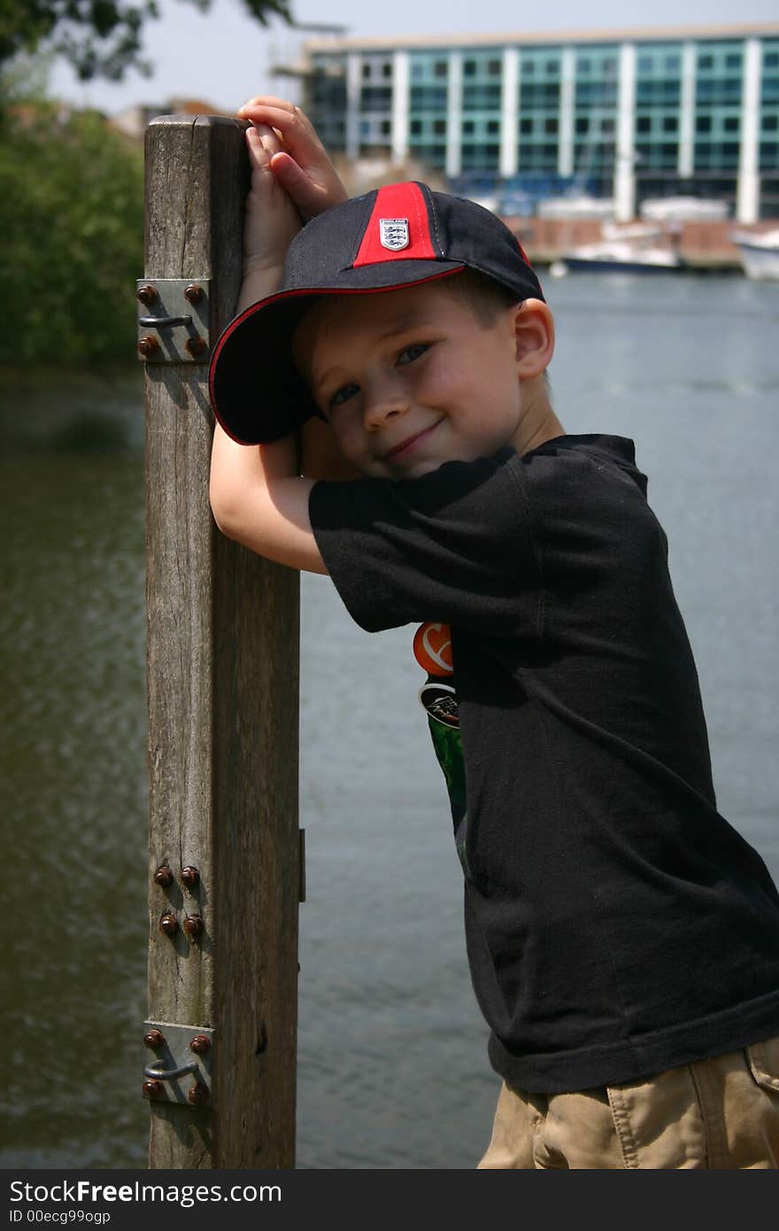 Young boy leaning on a post next to the river. Young boy leaning on a post next to the river