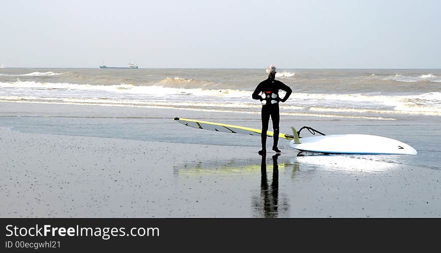 Surfer is surveying the ocean before going to surf along the North Sea coast in Belgium. Surfer is surveying the ocean before going to surf along the North Sea coast in Belgium.