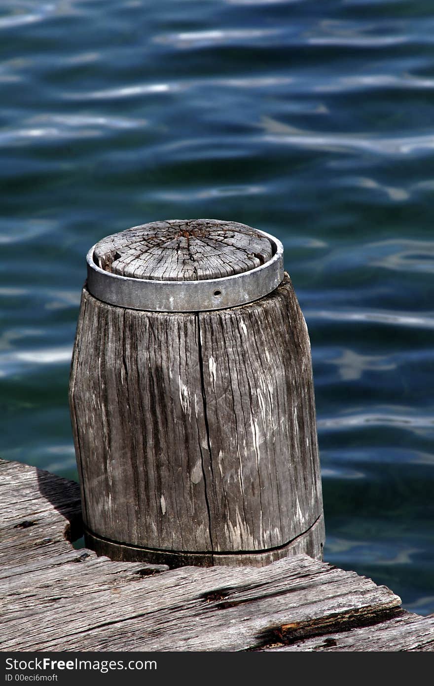 Wooden Pole Marking A Footpath Next To The Blue Ocean Surface