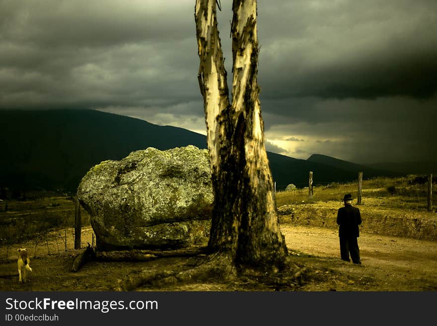 A traditional colombian farmer and his dog walk past a large rock and tree in the imposing colombian countryside with huge mountains and a turbulent sky in the background. A traditional colombian farmer and his dog walk past a large rock and tree in the imposing colombian countryside with huge mountains and a turbulent sky in the background.