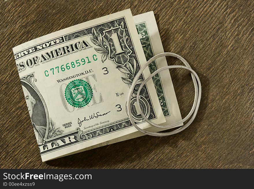 Dollar bill and rubber ring over dark wooden background. Dollar bill and rubber ring over dark wooden background