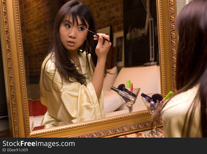 Reflection of girl applying eye makeup. Reflection of girl applying eye makeup