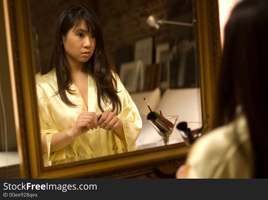 Reflection of pretty asian girl in a bathrobe looking pensive. Reflection of pretty asian girl in a bathrobe looking pensive