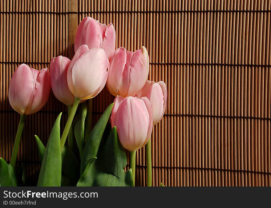 Bunch of pink tulips over wicker background