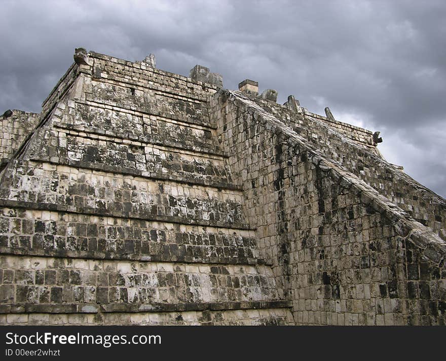 The close up of a pyramid with a cloudy background in Chichen Itza, Mexico.