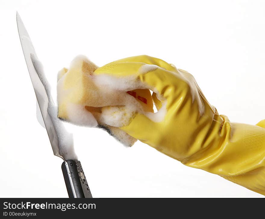 Hand in yellow rubber glove with yellow sponge and foam and knife. Hand in yellow rubber glove with yellow sponge and foam and knife