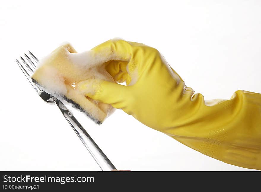 Hand in yellow rubber glove with yellow sponge and foam and fork. Hand in yellow rubber glove with yellow sponge and foam and fork