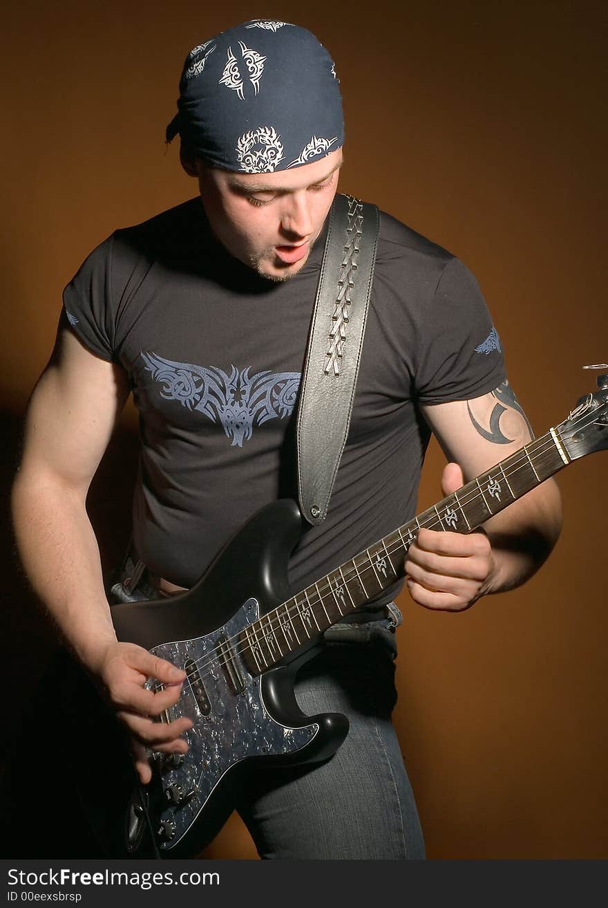 The man plays on a guitar on a red background. The man plays on a guitar on a red background