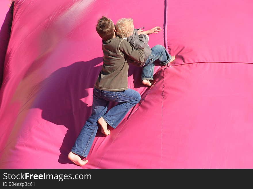 Boy pushing his brother up a large air cushion