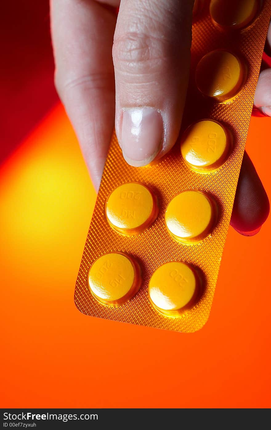 Pills on orange background with hand