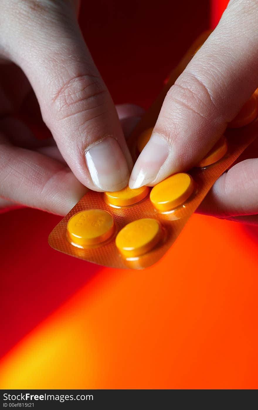 Pills on orange background with hand