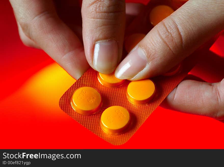 Pills on orange background with hand