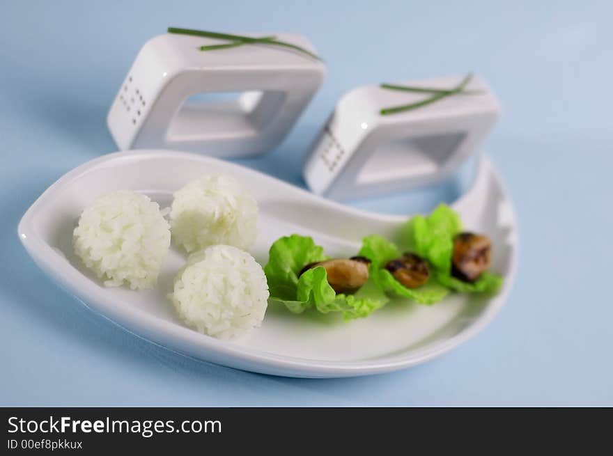 Shells with salad and rice on the blue background