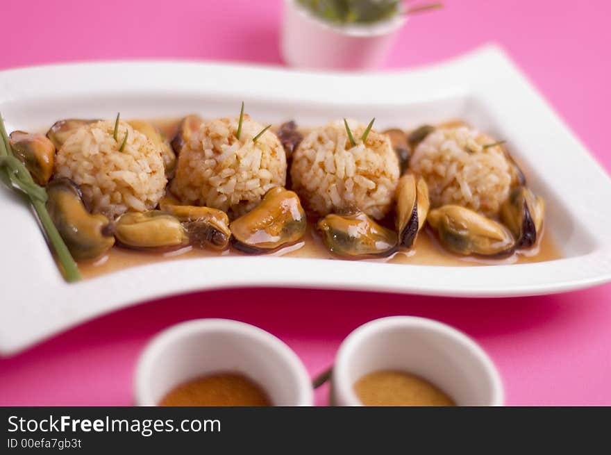 Shells with rice and green onion on the pink background