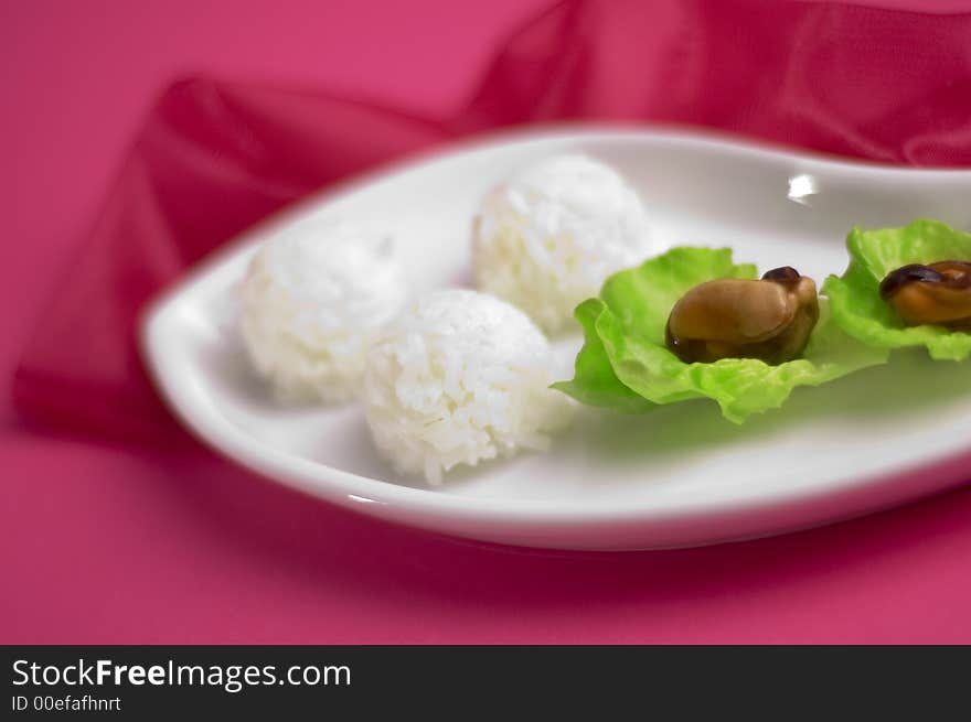 Shells with rice and salad on the pink background