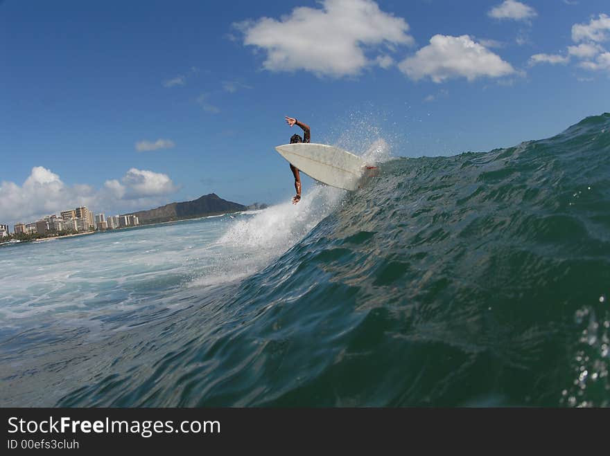 A surfer doing a frontside turn in hawaii with diamond head in the background. A surfer doing a frontside turn in hawaii with diamond head in the background