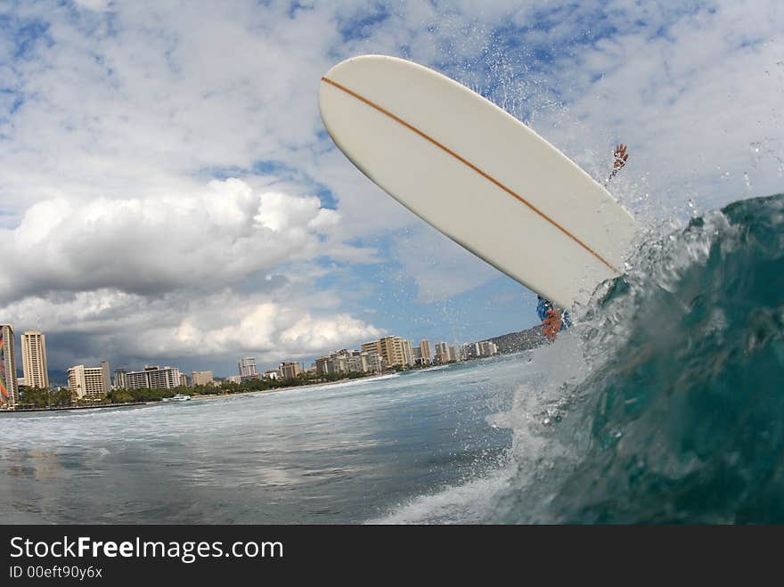 A longboard surfer doing a huge frontside off the lip in hawaii.