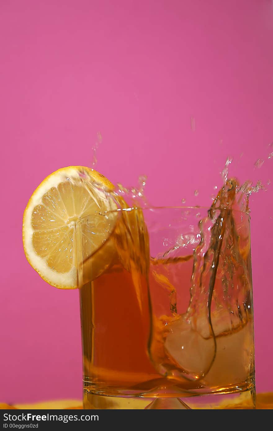 Ice floe falling into whisky glass causing from the splashes. Ice floe falling into whisky glass causing from the splashes