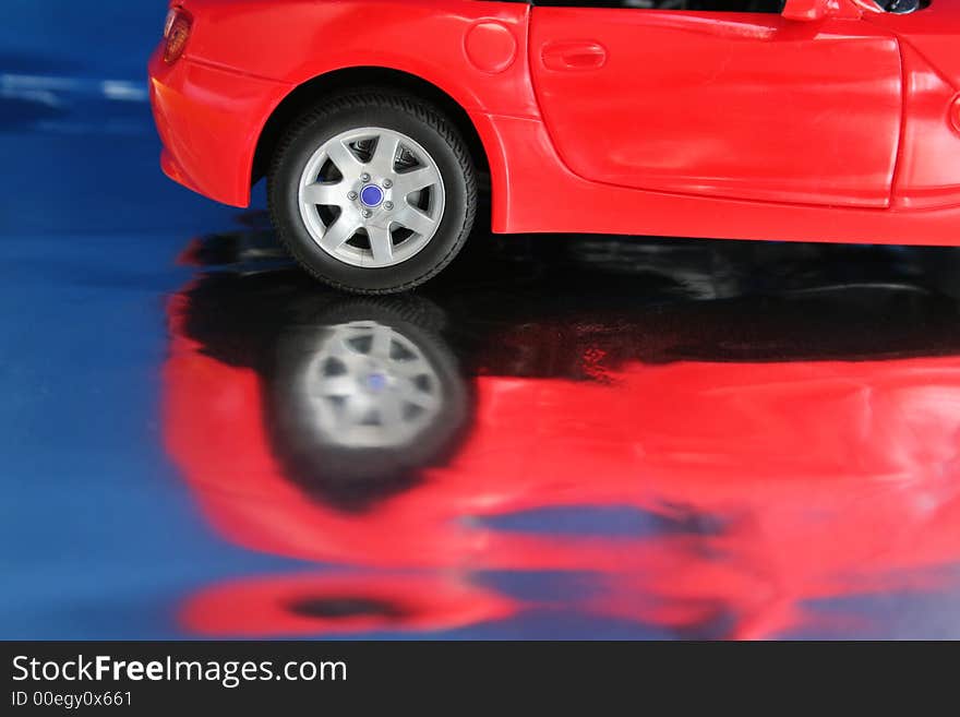 Red toy car close-up on a reflective surfice. Red toy car close-up on a reflective surfice.