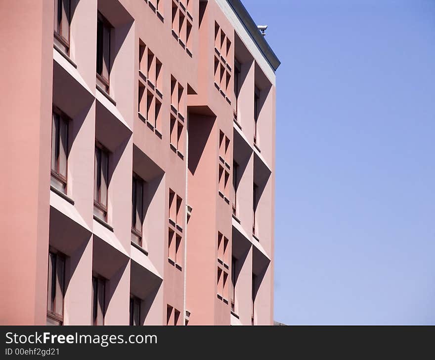 Tall pink building with triangular shadows against blue sky