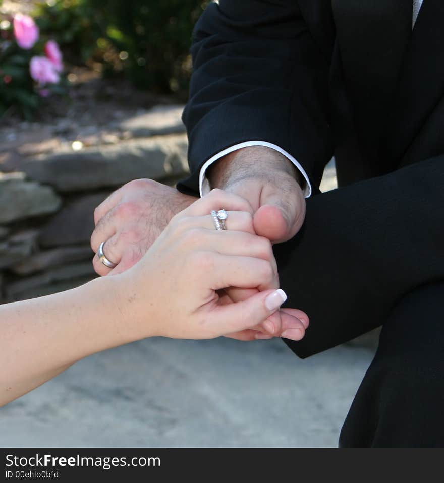 Detail of groom holding bride's hand showing wedding rings in formal attire. Detail of groom holding bride's hand showing wedding rings in formal attire