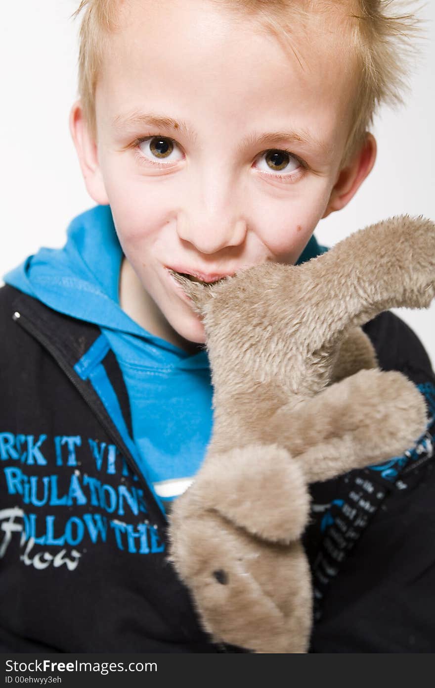 A young boy with a furry toy in his mouth. A young boy with a furry toy in his mouth