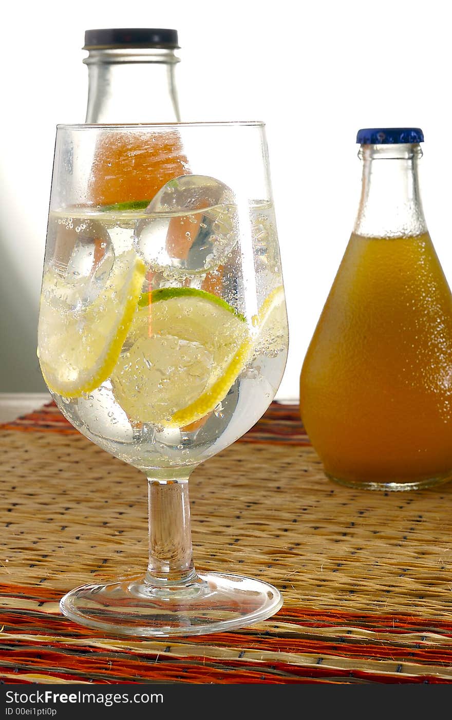 A glass of water with lemon and with bottle on the background. A glass of water with lemon and with bottle on the background