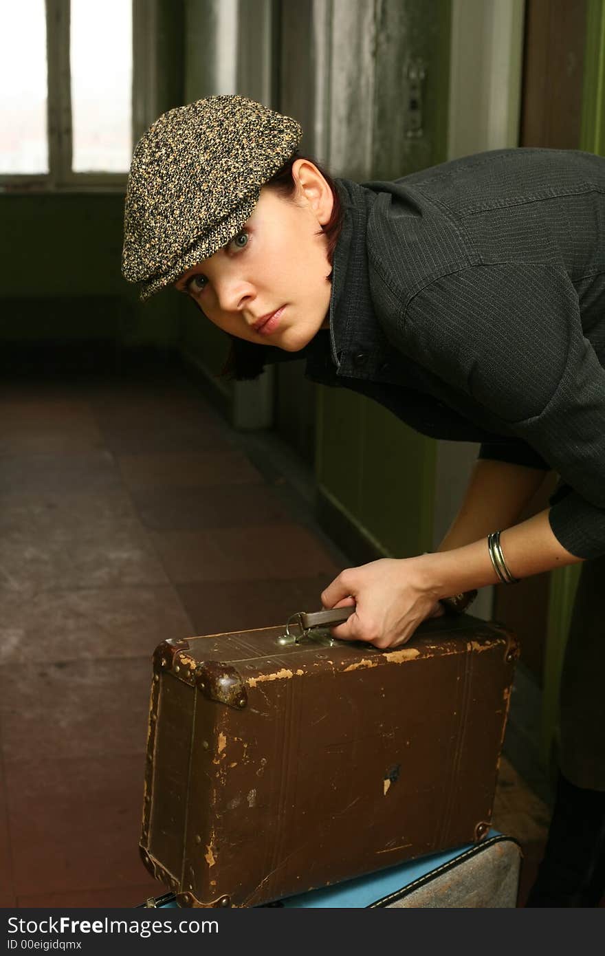 The beautiful woman in a cap with two old suitcases