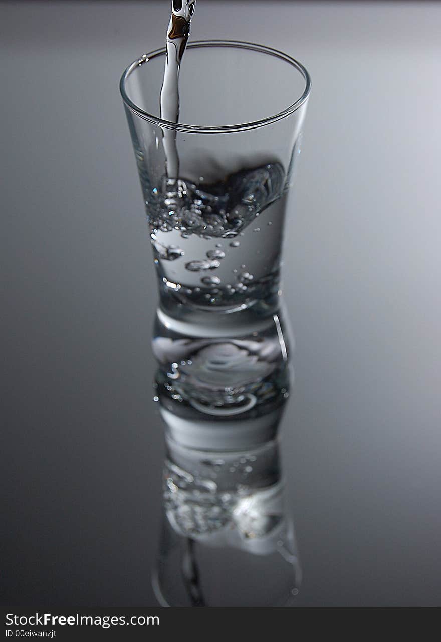 Vodka falling into glass agains white background