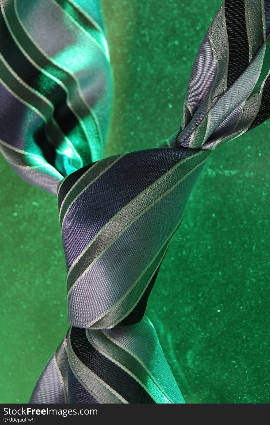 Striped purple silk tie on green. the tie is knotted