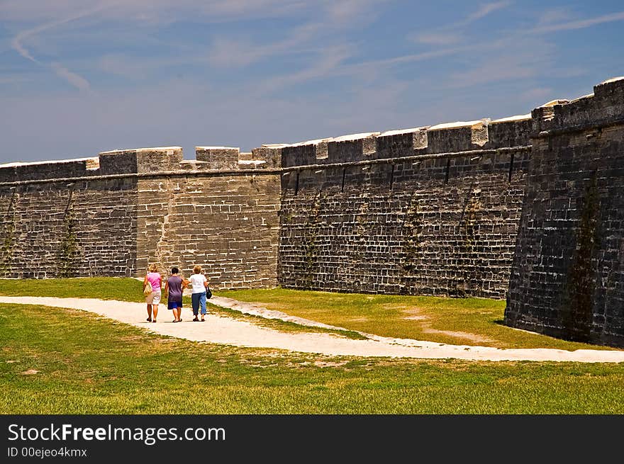 A view of three tourists as they walk along the dry moat that surrounds the old 15th century Spanish fort at St. Augustine, Florida. A view of three tourists as they walk along the dry moat that surrounds the old 15th century Spanish fort at St. Augustine, Florida.