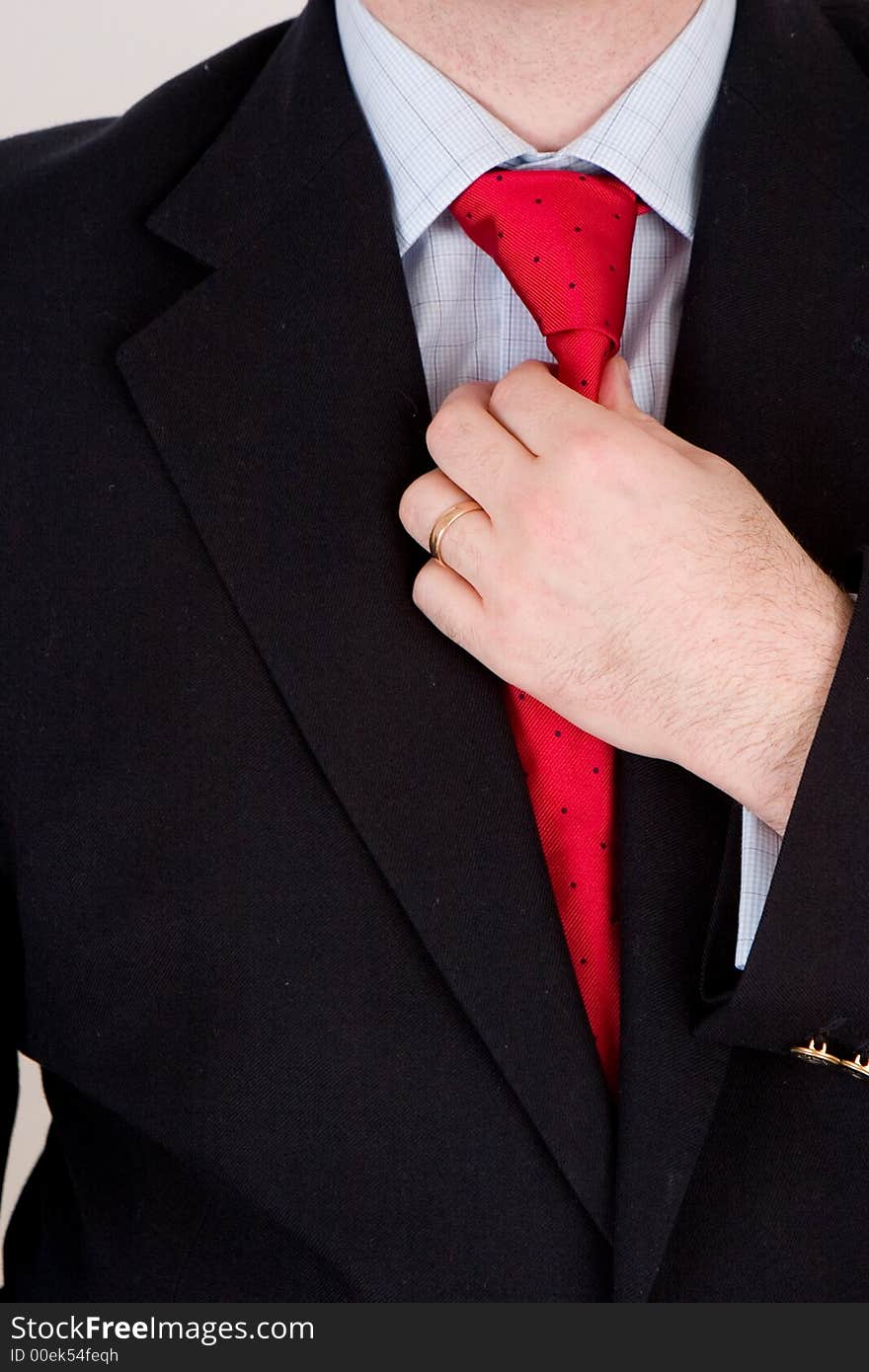 A business man in a blue suit, straightening his red tie