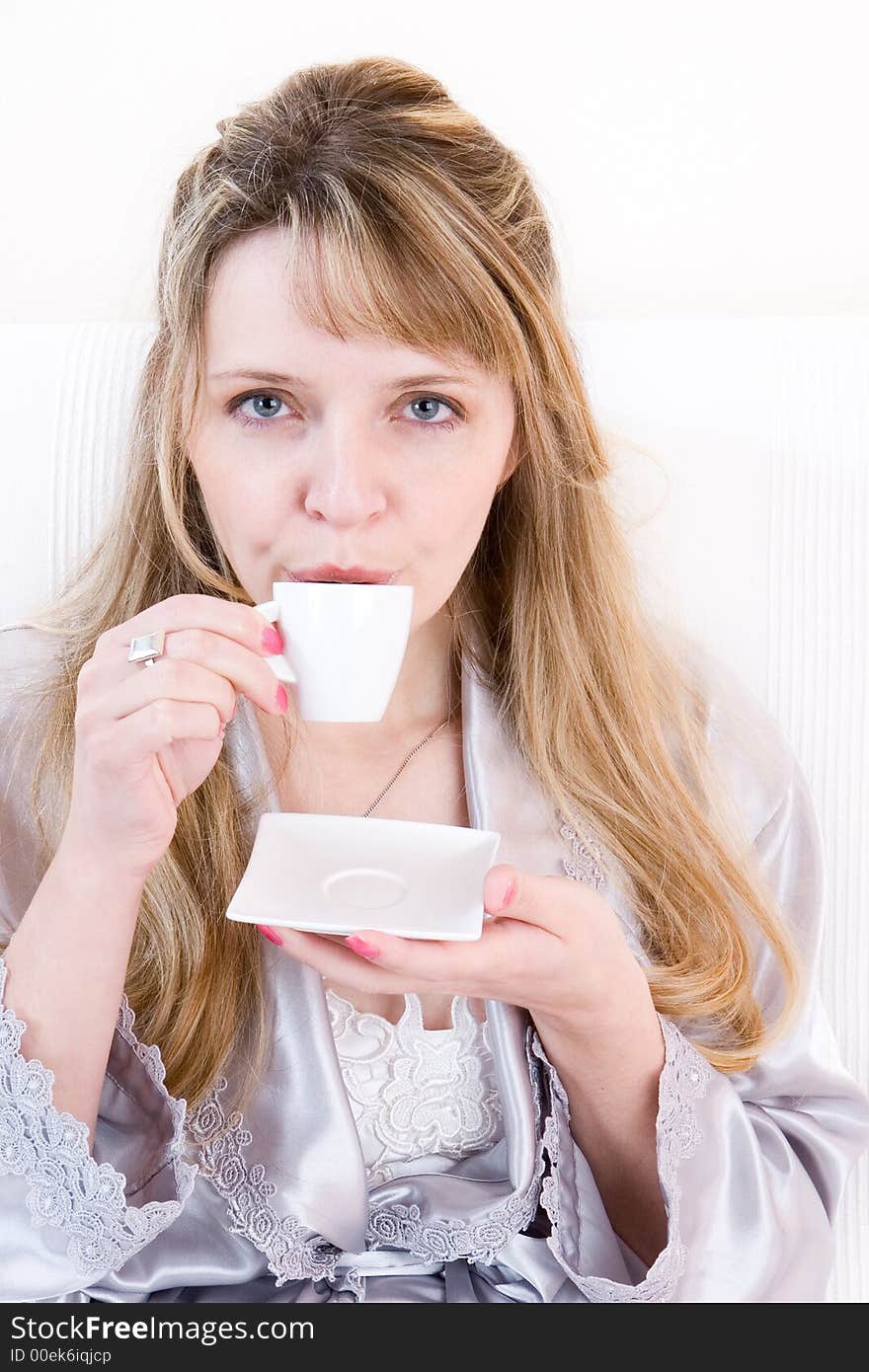 A women in a silver robe drinking a cup of espresso. A women in a silver robe drinking a cup of espresso