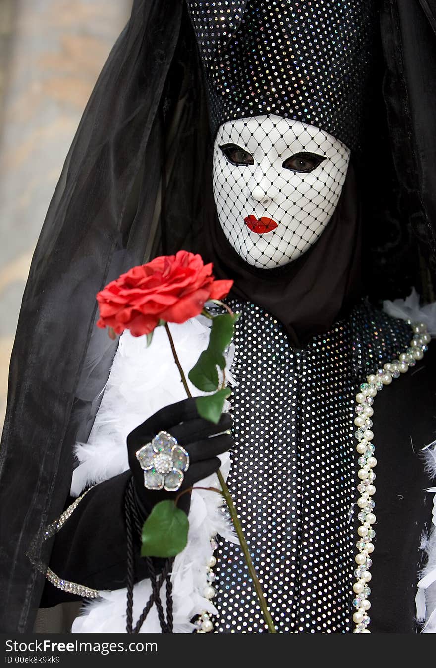 A venetian lady with a white mask, red lips and a red rose. A venetian lady with a white mask, red lips and a red rose