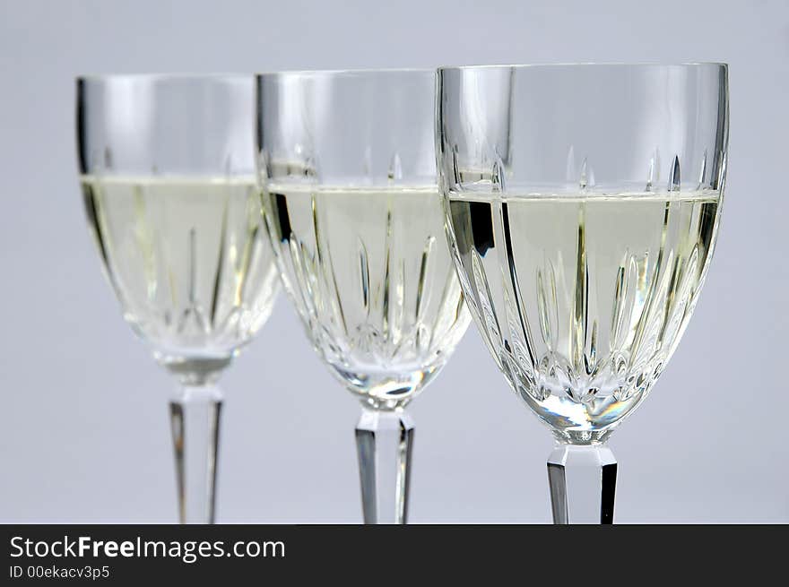 Three Glasses of white wine with selective focus over a neutral background. Three Glasses of white wine with selective focus over a neutral background.