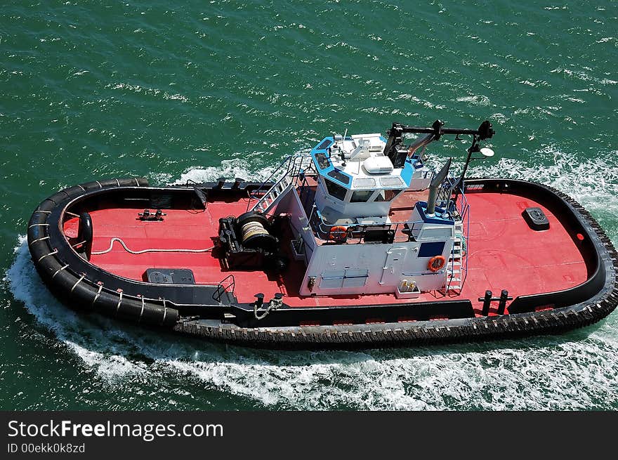 A red tug boat in the green ocean waters in Hawaii. A red tug boat in the green ocean waters in Hawaii.