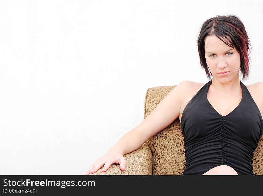 An attractive woman sits against a white wall. An attractive woman sits against a white wall.